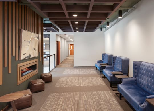 a waiting room with blue chairs and a fireplace
