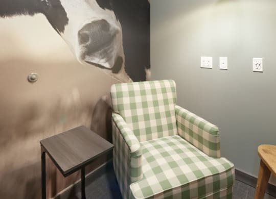 a painting of a cow on a wall next to a chair