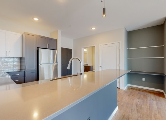 a kitchen with a large counter and a refrigerator at The Exchange Apartments, New Brighton, MN 55112