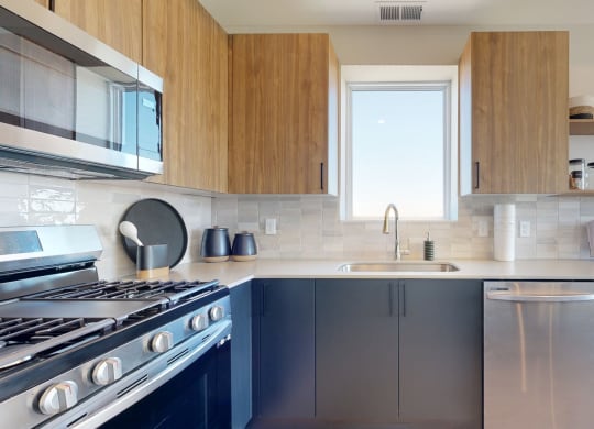 a kitchen with wood cabinets and stainless steel appliances at The Exchange Apartments, New Brighton, 55112