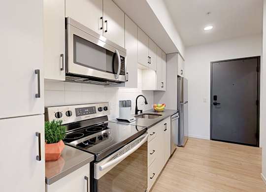 A modern kitchen with a stove, oven, microwave, and refrigerator.