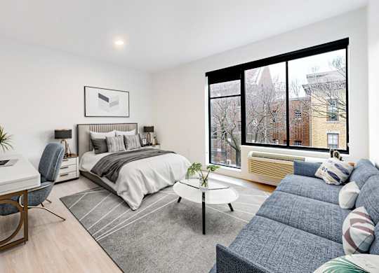 A well-lit bedroom with a bed, desk, and chair.