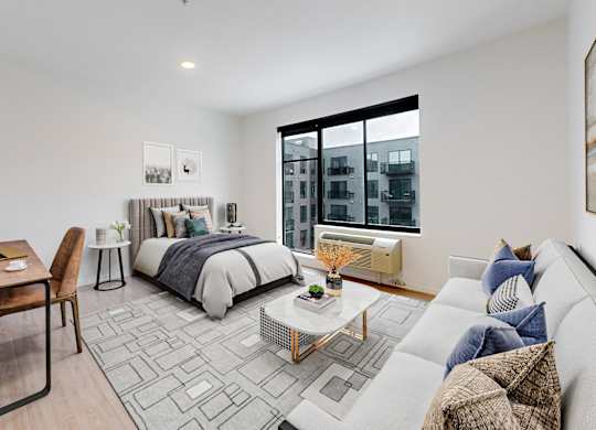 A modern bedroom with a large bed, a desk, and a couch.