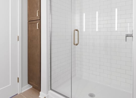 a bathroom with white tiles and a glass shower door