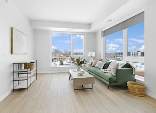 a living room with a green couch and large windows