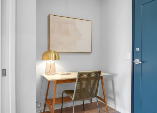 a small desk with a lamp and a book on it in a room with a blue door