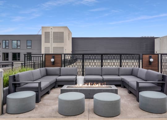 a patio with couches and a fire pit in front of a building