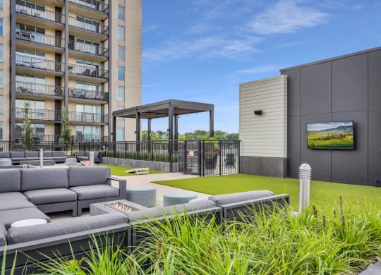 a grassy area with couches and a fire pit in front of an apartment building