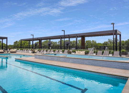 a swimming pool with chaise lounge chairs and trees in the background