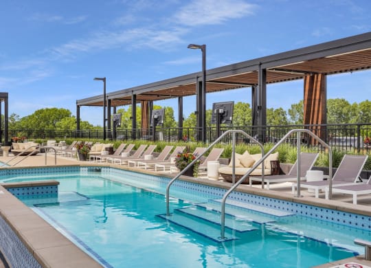 a resort style pool with lounge chairs and a pergola
