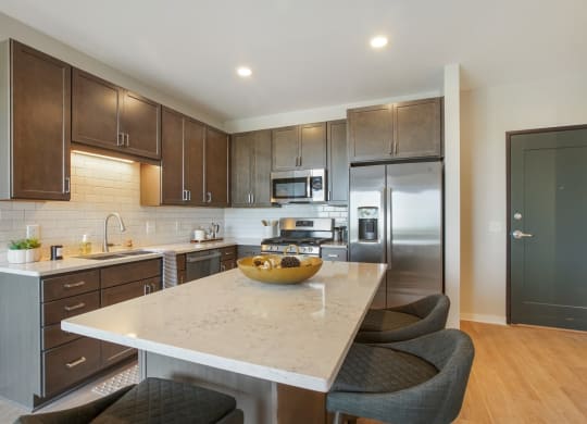a kitchen with dark wood cabinets and a white island with a wooden bowl on top of it