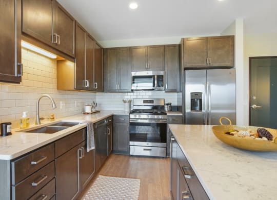 a kitchen with dark wood cabinets and white countertops