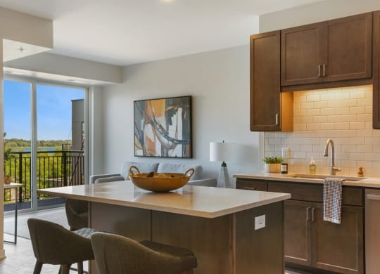 a kitchen with a large island and a sliding glass door leading to a balcony