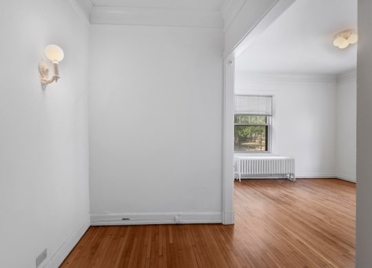 a bedroom with white walls and hardwood floors