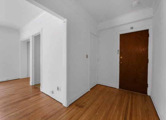 a bedroom with hardwood floors and white walls