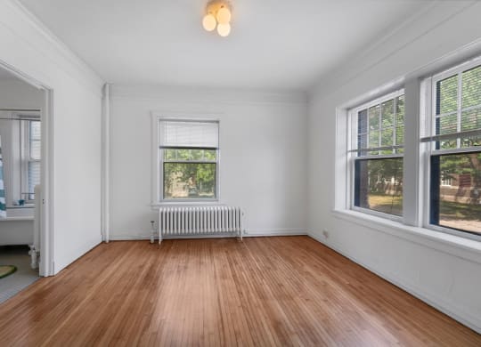 a bedroom with hardwood floors and white walls