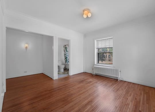 a bedroom with hardwood floors and a large window