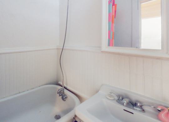 A white sink with a faucet and a window in a bathroom.