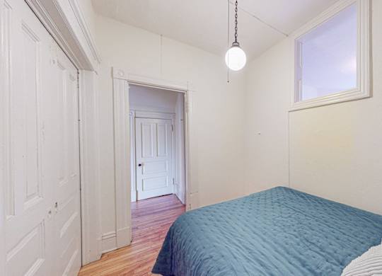 A bedroom with a blue bedspread and a window.