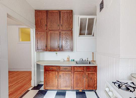 A kitchen with wooden cabinets and a black and white checkered floor.