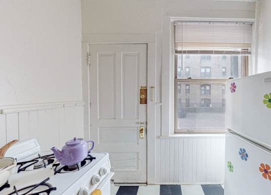 A white fridge with flower decals sits in a kitchen next to a stove.