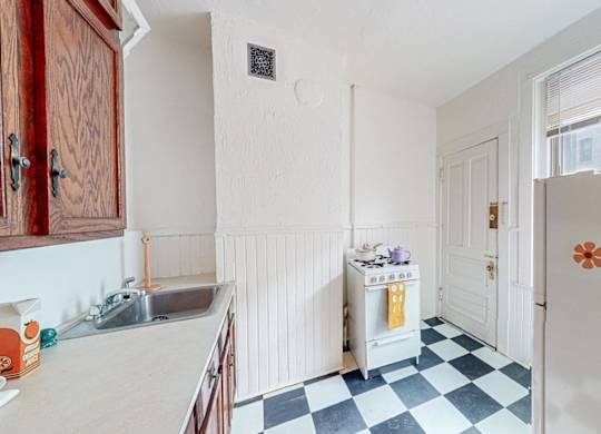 A kitchen with a checkered floor and a refrigerator with flower magnets.