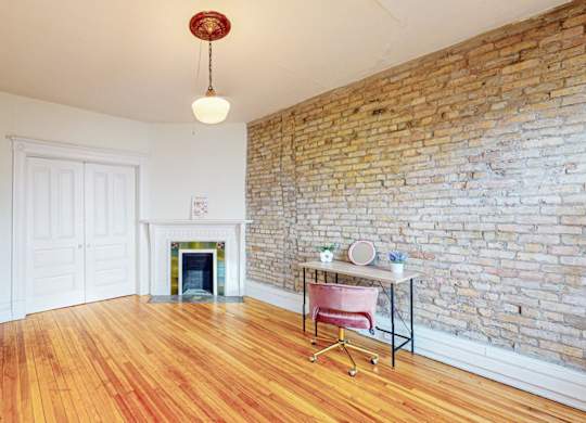 A room with a brick wall and a fireplace.