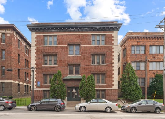 a red brick building with a black awning and cars parked in front of it