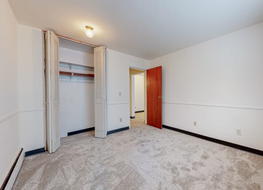 a bedroom with white walls and a closet with a wooden door