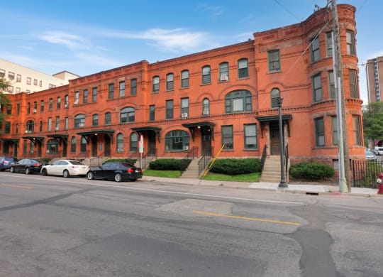 a red brick building on a street corner with cars parked in front of it