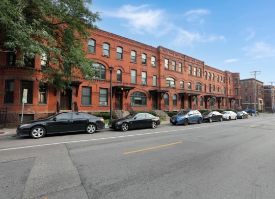 a row of red brick buildings with cars parked in front of them