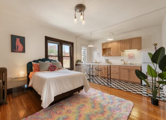 a bedroom with a bed and a kitchen in the background