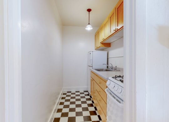 A Cozy Kitchen with Wood Cabinets and Black and White Checkered Flooring at The PArk Apartments in Minneapolis, MN