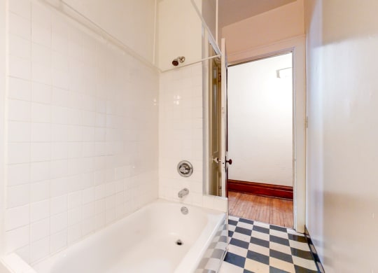 Bathroom with White Tiles and a Black and White Checkered Flooring at The Park Apartments in Minneapolis, MN