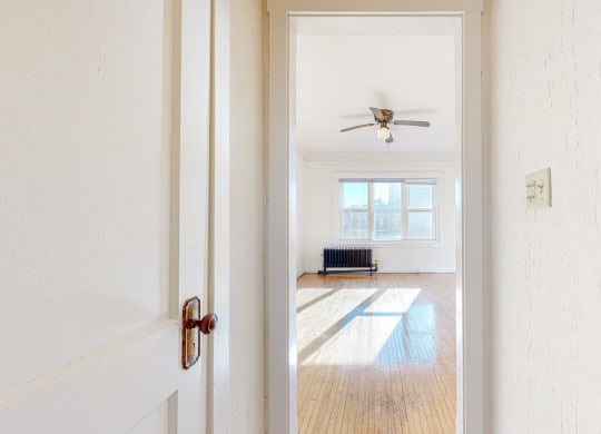A Spacious Living Room with White Walls, Restored Hardwood Flooring, and a ceiling fan at The Park Apartments in Minneapolis, MN 55403