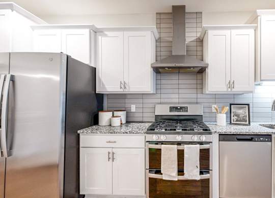 A modern kitchen with white cabinets and a black refrigerator.