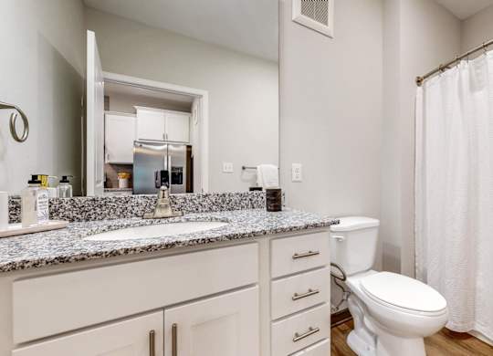 A white bathroom with a toilet, sink, and shower.