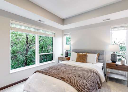 A bedroom with a large bed and a window overlooking a forest.