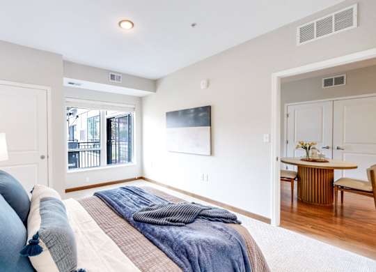 A bedroom with a large bed and a balcony outside.