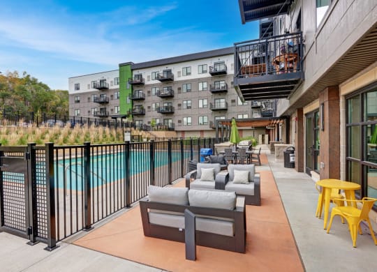 a poolside patio with furniture and a building in the background