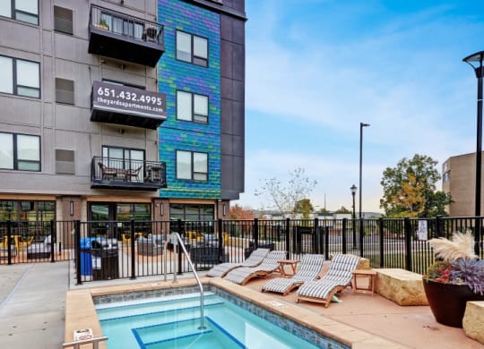 a swimming pool with lounge chairs next to a building