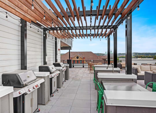 the outlook of the rooftop patio with barbecue grills and a pergola