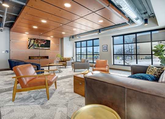 club room with chairs and couches, a fireplace, flat screen tv, and large windows