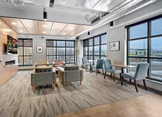 A communcal business center filled with lounge furniture, large windows, and a flat screen tv