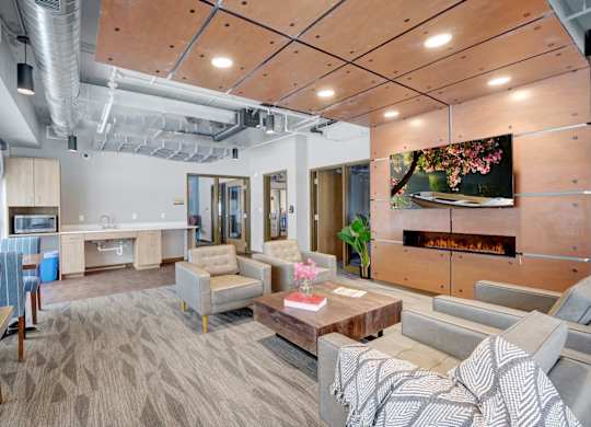 A communcal business center filled with lounge furniture, large windows, and a flat screen tv