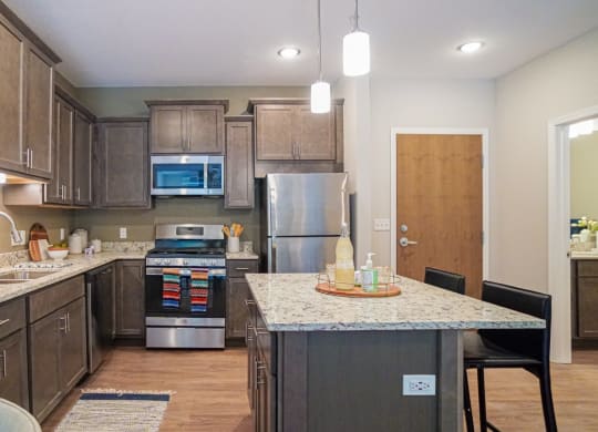 a kitchen with dark cabinets and granite countertops at The Yards and Backyards, Saint Paul, 55075