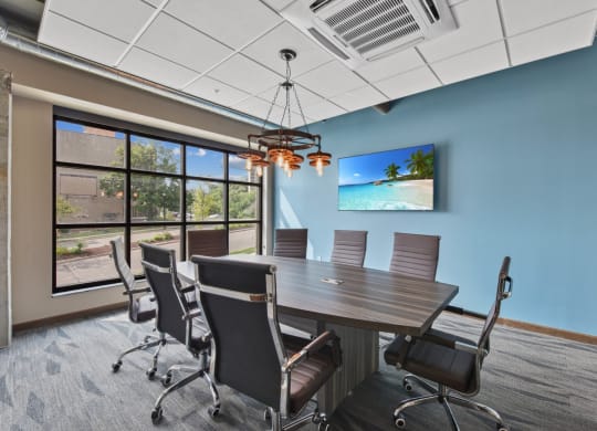 a conference room with a table and chairs and a tv on the wall