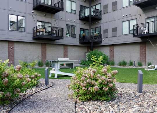A courtyard with a bench and a small garden with flowers.