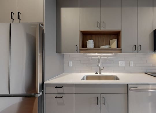 A modern kitchen with a stainless steel refrigerator, a white sink, and a microwave above the stove.at Tyler Street Stacks, Minneapolis, MN 55413