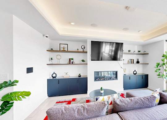 A modern living room with a grey sofa and a red rug.